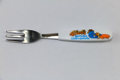 One small fork with a white plastic handle, there is an image of two seals wearing hats, one blue mother seal feeding her orange baby seal from a bowl with a spoon and the words 'Atlantis Marine Park Western Australia'