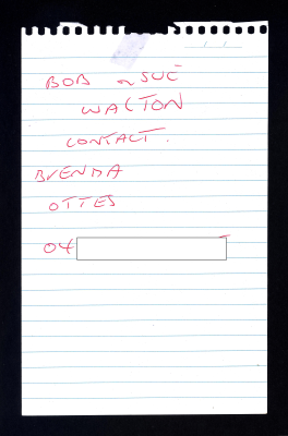 White piece of blue lined note paper, torn out from pad with six lines of hand written text in red pen