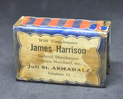 Rectangle metal match box holder with the text 'With Compliments James Harrison General Storekeeper Produce Merchant, etc Jull Street Armadale Telephone 13