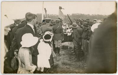 Crowd, both soldiers and civilians gathered at a burial site.