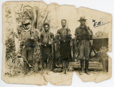 Two Australian soldiers and two Papuan soldiers holding rifles over left shoulder.