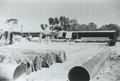 Black and White photograph Electweld Steel.  Cement lined pipes curing plant in background