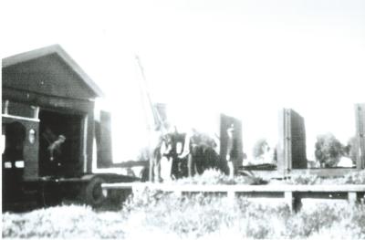 Black and White photograph.  Kellerberrin Railway Station.  Finished pipe being loaded onto rail