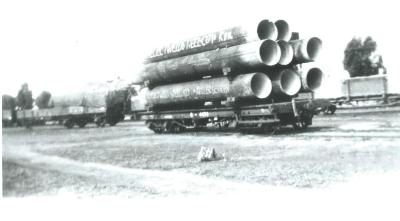 Black and White photograph.  Refurbished 30 inch mains being railed out from Kellerberrin