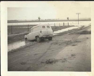 Black and White photograph showing Van crashed off road during floods