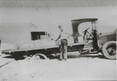 Black and white photograph.  Bogged Vulcan truck outside Marchant's shop
