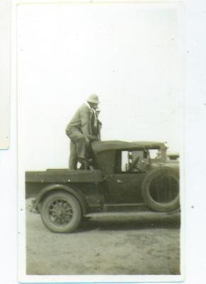 Black and White photograph. Men on back of ute