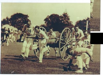 Black and white photograph. Kellerberrin Volunteer Fire Brigade running team competing at Perth Oval in cart event