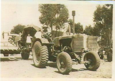 Black and White photograph.  Tractor and Farm Machinery with young girl