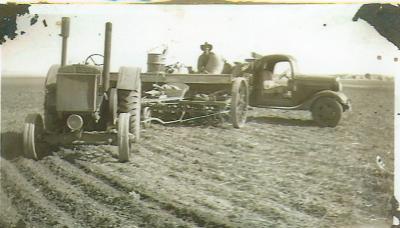 Black and White photograph.  Farm machinery with man working