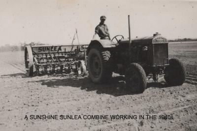 Black and White photograph.  A Sunshine Sunlea combine working in the 1940's