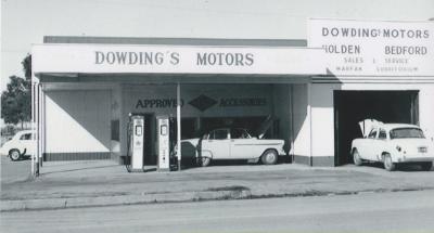 Black and White photograph.  Dowding Motors.  Fuel Bowsers outside and 3 vehicles waiting for repairs