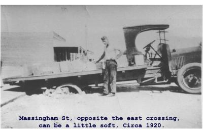 Black and White photograph "Massingham Street, opposite the East crossing can be a little soft"  Circa 1920.  Truck bogged on railway crossing