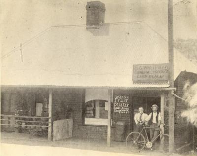 OLIVER WHITFIELDS PRODUCE STORE WITH OLIVER WHITFIELD [AND WIFE EVA] AND BICYCLE