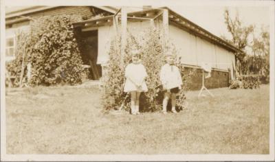 PHOTOGRAPH (DIGITAL COPY): TWO CHILDREN ON LAWN INFRONT OF HOUSE, WHITE FAMILY