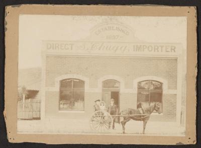 PHOTOGRAPH: SIMON CHUGG, IMPORTER, AND DAUGHTERS OUTSIDE CHUGG'S BUILDING