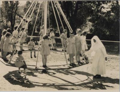 PHOTOGRAPH (COPY): NUN AND CHILDREN PLAYING ON A SWING, ST. JOSEPH'S ORPHANAGE