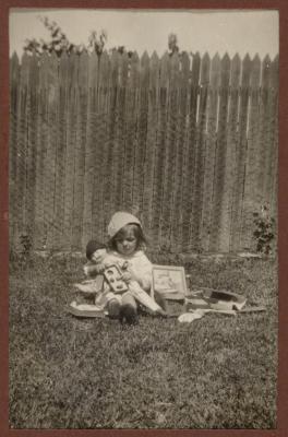 PHOTOGRAPH (DIGITAL): THELMA CONGDON WITH A DOLL IN A GARDEN, FROM CONGDON FAMILY ALBUM