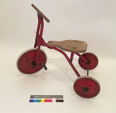 TRICYCLE: RED METAL WITH WOODEN SEAT, JUSTIN DIGGINS