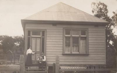 POSTCARD: FAMILY IN FRONT OF HOUSE, FROM ALBUM 1, THELMA GREEN COLLECTION